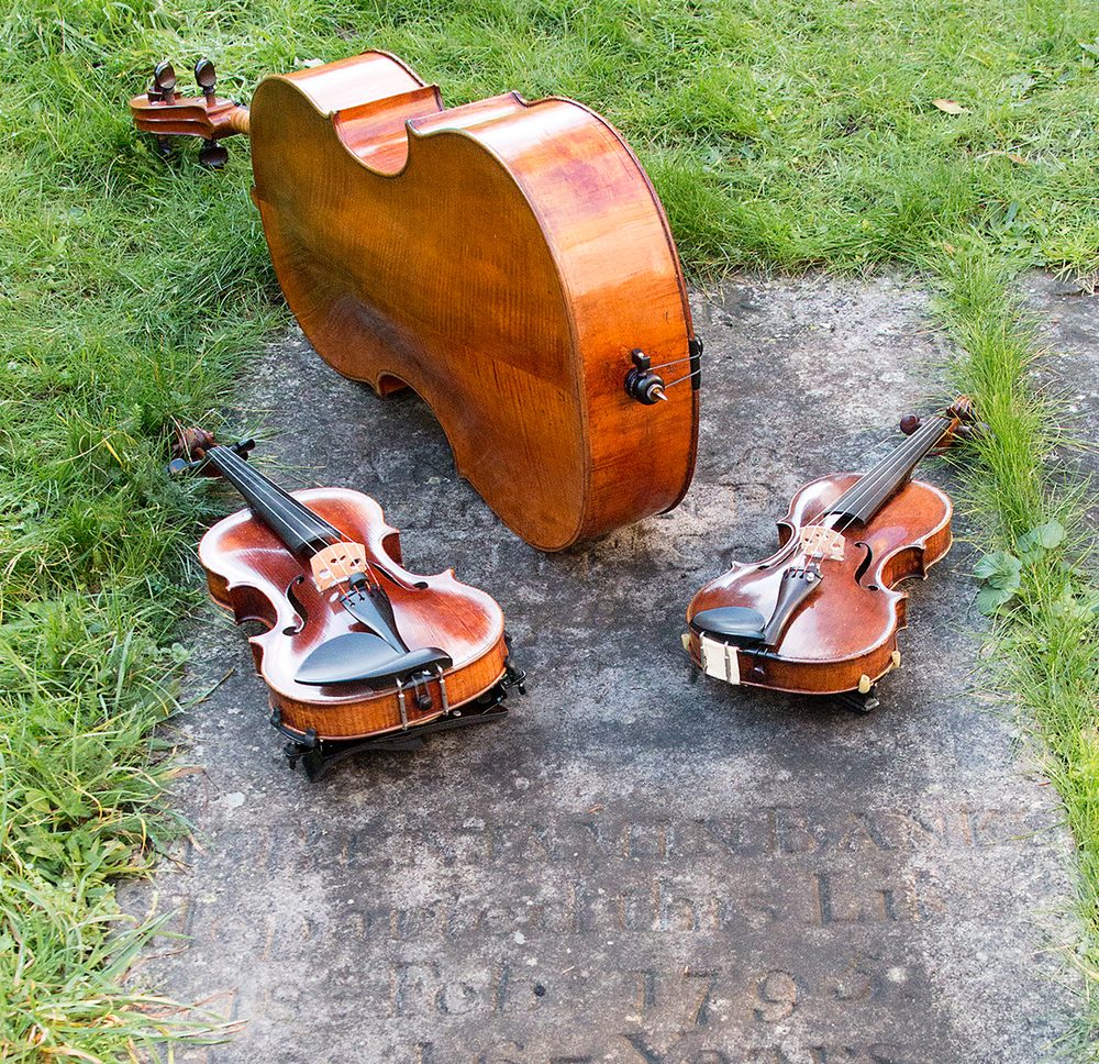 Two violins and a cello resting on Benjamin Banks' gravestone